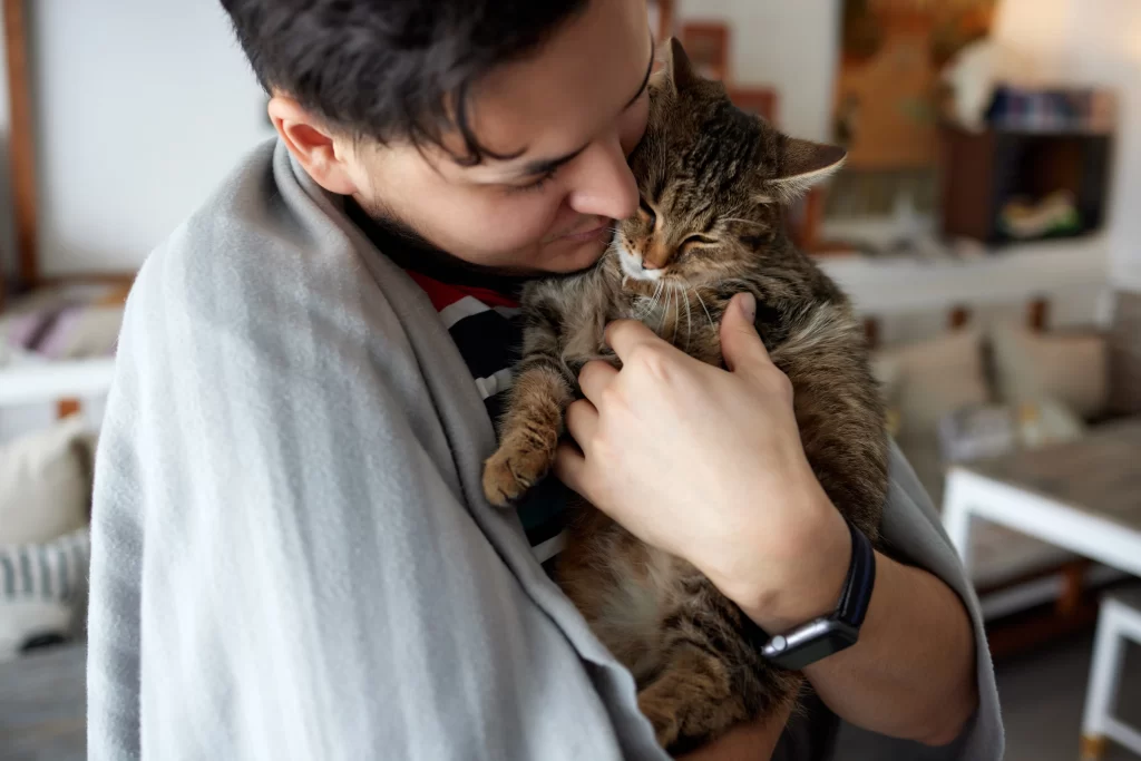 Hombre joven sostiene a su gato.